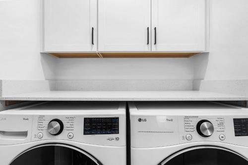 two washing machines in a kitchen with white cabinets at Stonegrove Residence in Blaine