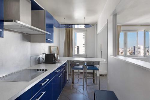 une cuisine avec des placards bleus et une table avec des chaises dans l'établissement BM-Confort & Calme 5 pers Rue des Mariniers, à Paris