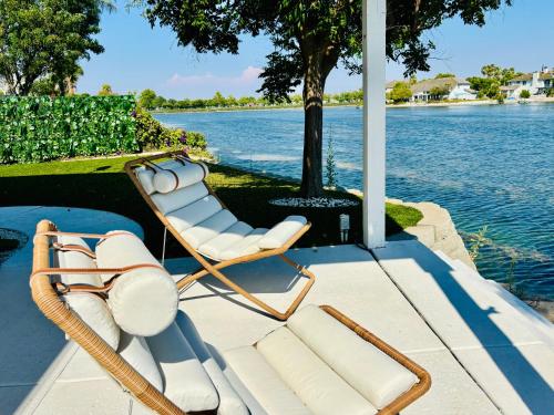 Un par de sillas sentadas en un muelle junto al agua. en Experience Serenity Luxe 4BDR Lake House 25ft Pool, en Elk Grove