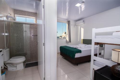 a bedroom with a bed and a shower and a toilet at Pousada Paraná in Penha
