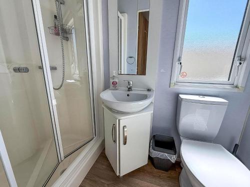 a bathroom with a sink and a shower and a toilet at Gorgeous 6 Berth Caravan With Decking Area, Dovercourt Holiday Park Ref 44510A in Great Oakley