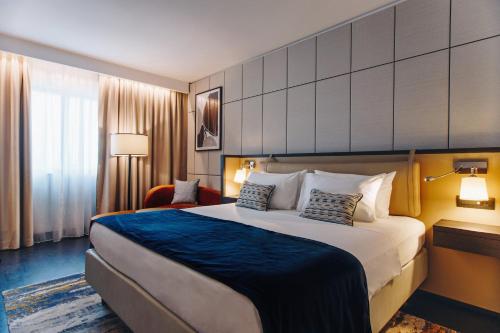 a hotel room with a large bed and a chair at Crowne Plaza Belgrade by IHG in Belgrade