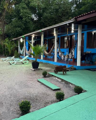 a blue building with hammocks and a house at Pousada Pé Na Areia - ilha do mel in Paranaguá