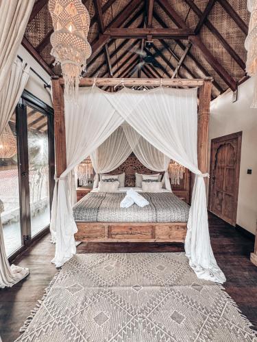 a bedroom with a canopy bed with curtains and a rug at Casa Magick boutique Villa in Gili Islands