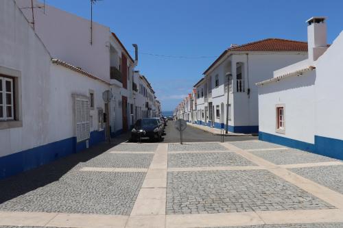 a street with a car parked on a cobblestone street at Quartos Vasco da Gama in Porto Covo