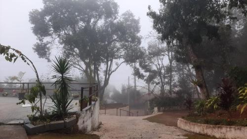 a foggy street with trees and a fence and a gate at Espaço Azul in Ibiúna