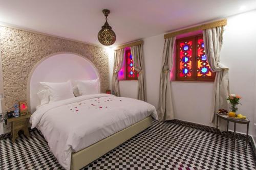 a bedroom with a white bed and stained glass windows at Riad Amor - Suite & Spa in Fès