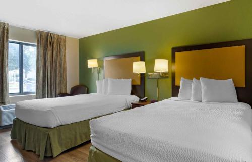 two beds in a hotel room with green walls at Extended Stay America Suites - Houston - NASA - Johnson Space Center in Nassau Bay