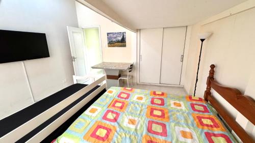 a bedroom with a bed and a flat screen tv at Studio 102 Pitangueiras no térreo - ar condicionado - na quadra da praia! in Guarujá