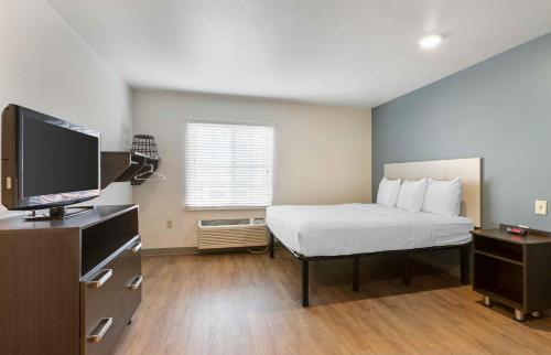 a small room with a bed and a television at Extended Stay America Select Suites - Phoenix - North in John C Lincoln Helistop