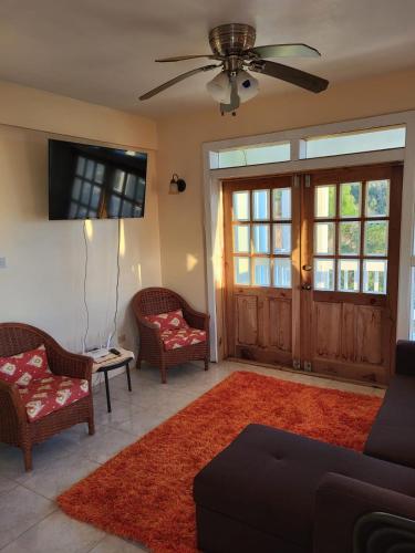 a living room with a couch and chairs and a tv at Scotland Villa-Dominica in Canefield