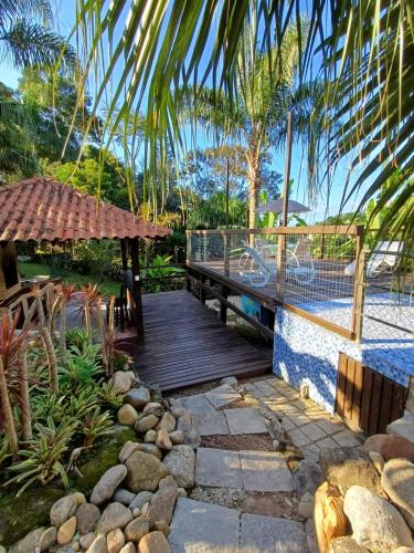 a wooden deck with a bench and a table at Suíte Pachamama in Bombinhas
