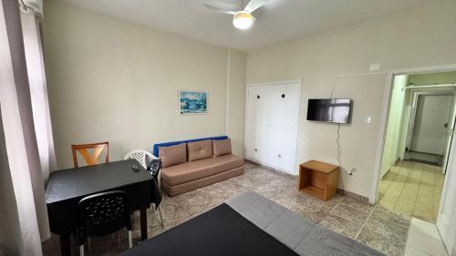 un salon avec un canapé, une table et une télévision dans l'établissement Studio 308 nas Pitangueiras - na quadra da praia!, à Guarujá