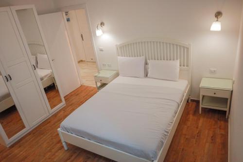 a bedroom with a bed with white sheets and a mirror at Andalusia Blue Beach Hurghada in Hurghada