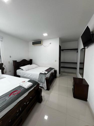 a room with two beds and a tv on the wall at Scherezade Hotel&Resorts in Aguachica