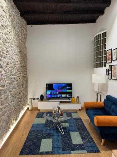 a living room with a couch and a tv on a wall at Aria B&B - apartment in the historic center in Spoleto