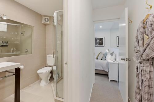 a bathroom with a shower and a toilet and a bed at Queenstown House Bed & Breakfast and Apartments in Queenstown