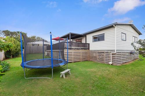 a swing in a yard in front of a house at Warm Cosy holiday home right in town in Raglan