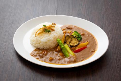 a white plate of food with rice and vegetables at Oarks Canal Park Hotel Toyama in Toyama