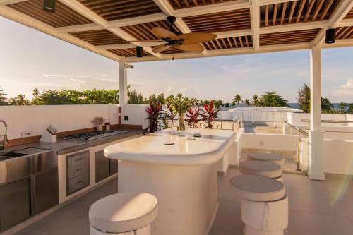 an outdoor kitchen with a large island and stools at New Beachfront Penthouse Punta Popy in Las Terrenas