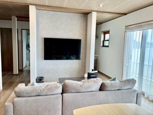 a living room with a couch and a flat screen tv at OceanフロントYASHIRO鴨川 目の前に海が広がる広々一軒家貸切 11名 in Kamogawa