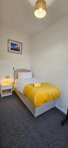 a bedroom with a bed with a yellow blanket on it at OG Stays V in Pallion