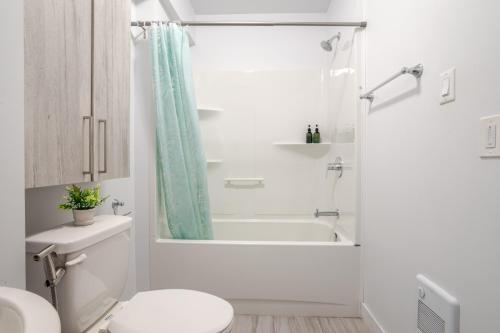 a white bathroom with a shower and a toilet at Fashionable 3BR in Griffintown in Montréal