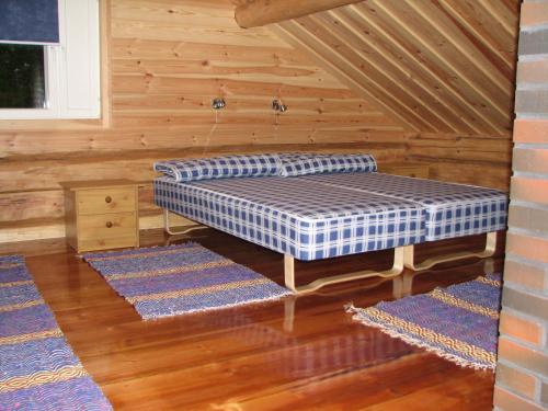 a mattress bed in a room with three rugs at Pitkäniemen Lomamökit in Joutsa