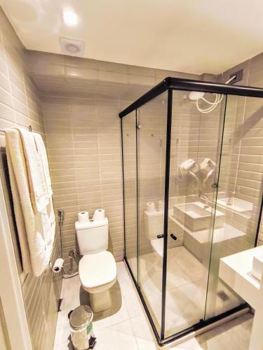 a bathroom with a toilet and a glass shower at Flat Beira Mar, Arpoar João Pessoa in João Pessoa