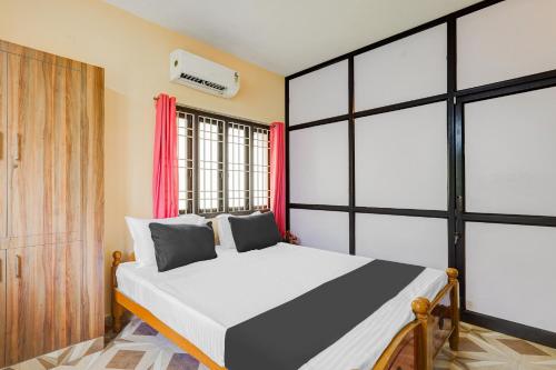 a bedroom with a large white bed with red curtains at Super Hotel O Velachery Near Devi Karumariamman Nagar Extension in Chennai