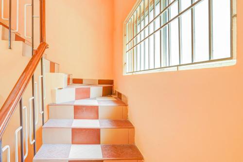 a staircase with orange walls and a window at Super Hotel O Velachery Near Devi Karumariamman Nagar Extension in Chennai
