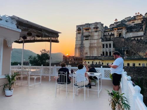 a group of people sitting at tables on a balcony at The Castle View Homestay in Būndi