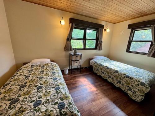 two beds in a room with two windows at Villa Grace in Hokuto