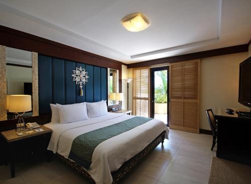 a bedroom with a large bed and a desk with a desk at Henann Regency Resort and Spa in Boracay