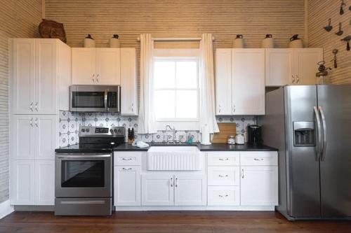 a kitchen with white cabinets and a stainless steel refrigerator at The Cahill- Magnolia Brewery House c 1894 in Waco