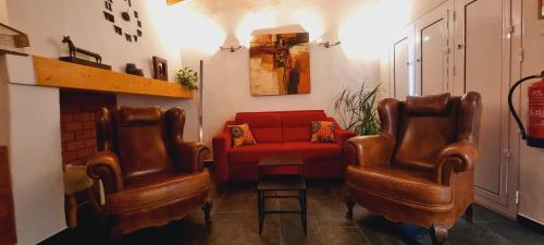 a living room with two chairs and a red couch at Charme de Monsaraz in Monsaraz
