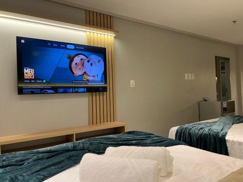a hotel room with two beds and a flat screen tv at Quality Suítes - Ao lado da Orla - Flat com Vista Mar in João Pessoa