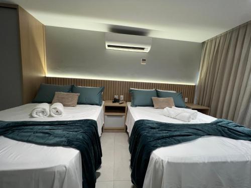 a hotel room with two beds with towels on them at Quality Suítes - Ao lado da Orla - Flat com Vista Mar in João Pessoa