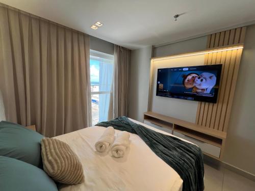 a bedroom with a bed with a tv on the wall at Quality Suítes - Ao lado da Orla - Flat com Vista Mar in João Pessoa
