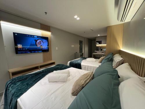 a hotel room with two beds and a flat screen tv at Quality Suítes - Ao lado da Orla - Flat com Vista Mar in João Pessoa