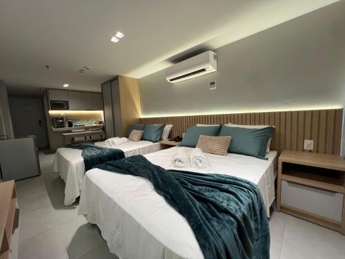 a hotel room with three beds and a kitchen at Quality Suítes - Ao lado da Orla - Flat com Vista Mar in João Pessoa