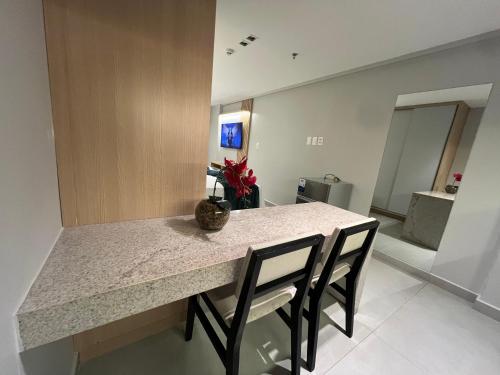 a kitchen with a table with chairs and a counter top at Quality Suítes - Ao lado da Orla - Flat com Vista Mar in João Pessoa