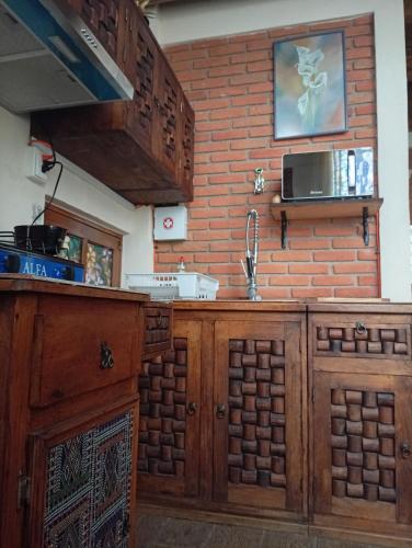 a kitchen with wooden cabinets and a brick wall at "Arte en el desván" Rustic loft - Desván rústico in Tenancingo de Degollado