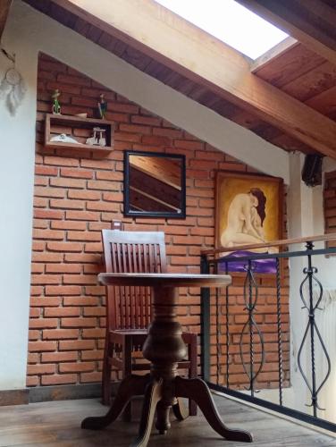 a table and chair in a room with a brick wall at "Arte en el desván" Rustic loft - Desván rústico in Tenancingo de Degollado