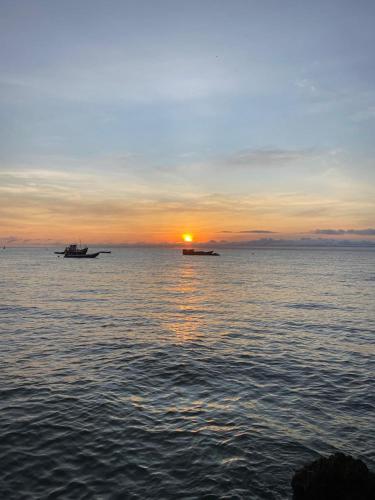 a sunset over the ocean with two boats in the water at Hotel Katamaran in Capurganá