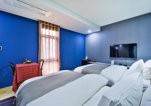 a blue room with two beds and a flat screen tv at JS Boutique Hotel in Hwaseong