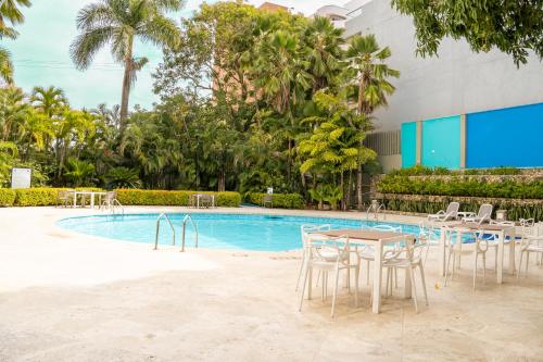 a pool with tables and chairs in front of a building at Hotel Barranquilla Plaza in Barranquilla