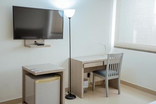 a desk with a television and a desk with a chair at Hotel Barranquilla Plaza in Barranquilla