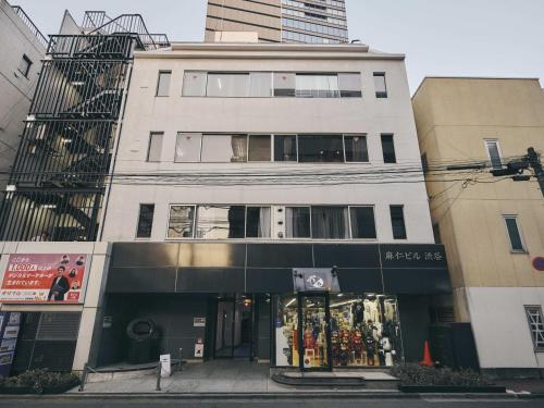 a tall white building with a store in front of it at illi Mani Shibuya in Tokyo