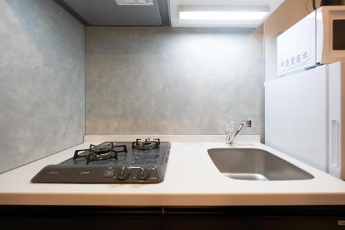 eine Küche mit Herd und Spüle in der Unterkunft Bellie Sangenjaya by Tranova in Tokio